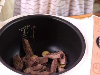 8、电饭煲牛肉干,电饭煲里放姜片 倒入所有牛肉条