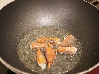 4、鲜虾粉丝煲,锅中倒入少许油，油热后，将虾头放入锅中煸炒出虾油，然后把虾头取出扔掉锅中留下虾油。