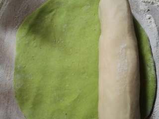 8、翡翠饺子,取适量菠菜面团擀成面皮,再放上撮成圆条白色面团。
