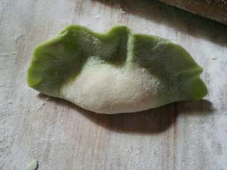 13、翡翠饺子,把面皮对折和上,把饺子放在双手食指上,两大拇指往食指上推,两虎口处用力一挤就完成啦。