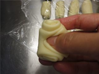 22、最爱这酥软的--蛋黄酥,拿起一个擀卷好的面团在中间按一下，使2端向上翘起。用手把不规则的边缘向中间收拢