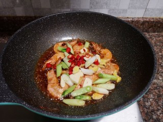 9、麻辣干锅虾,放入生姜、大蒜、蒜苗头和小米辣翻炒片刻。