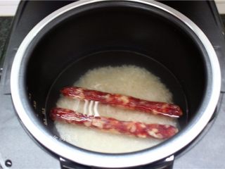 2、葫芦瓜腊肠冬菇焖饭,掏干净大米，倒入电饭锅中，加上适量清水，将腊肠洗净铺在上面同煮，腊肠渗出的油脂香味浸润大米，增加米饭的香气