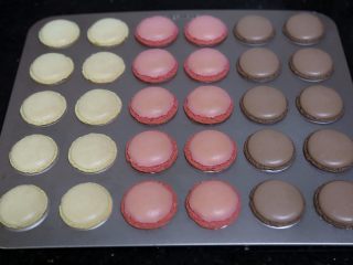 13、蜗牛马卡龙,烤好后取出放凉，这个时候可以制作巧克力干纳许，小火煮淡奶油至边缘冒小泡后离火，把白巧克力币倒入淡奶油中，5分钟后拌匀即可，可放入冰箱冷藏2小