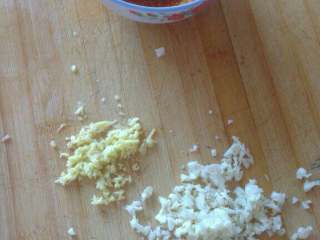 5、自制(爽口咸萝卜条),蒜和姜切碎末，拿一净碗加适量辣椒面儿，淋入少许水搅拌稀释；