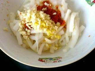 6、自制(爽口咸萝卜条),放萝卜条儿容器中加入蒜  姜末，和稀释好的辣椒面儿；