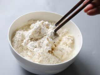 2、酱香饼,用筷子将面团和水拌成粗糙的面团。