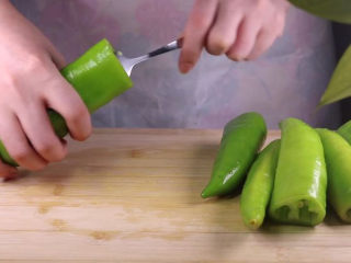 5、往青椒里塞入半斤金针菇，这味道绝了！,接着我们可以借助勺子将青椒肚子里的辣椒籽挖出。