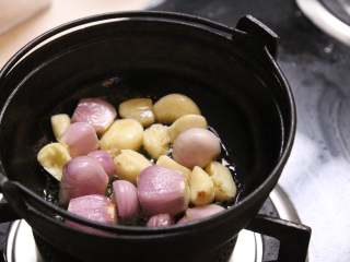 12、台式三杯鸡,将拍碎的干葱和蒜头都放入铁锅中爆香,等到蒜头和干葱的香味出来,颜色变的金黄色时,倒入鸡肉