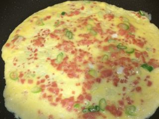 10、火腿葱花厚蛋烧,再加入半勺转动锅让鸡蛋液慢慢的流动成圆形,薄厚适中受热均匀