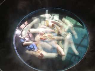 3、泰式凤爪,如图烧一锅开水倒入料酒，放入鸡爪和姜片煮15分钟