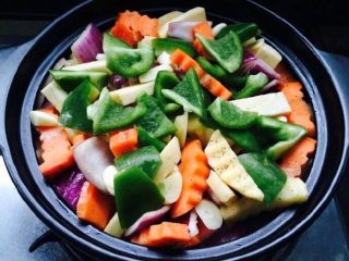 4、三汁鸡翅焖锅,热锅入黄油，化开后放蒜瓣和洋葱炝锅，放入切好的蔬菜翻炒一下，加入盐、黑胡椒。然后放肉