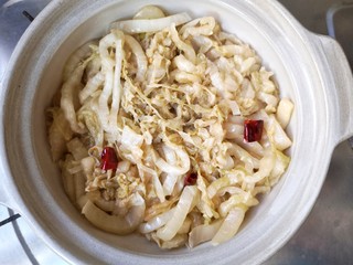 13、酸菜排骨暖锅,取砂锅,底部放入炒好的酸菜丝。