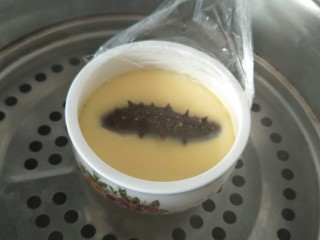 9、海参蒸蛋,蒸七到八分钟后，打开锅盖，掀开保鲜膜把处理好的海参放入碗中，盖上保鲜膜继续蒸三到五分钟。