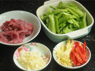 1、豌豆烧牛肉,所有的食材都处理好，牛肉切细丝，豌豆去掉两边的经络，蒜切末，姜切丝，红辣椒切丝