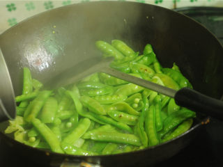 7、豌豆烧牛肉,锅里倒入少量的油，烧至八成热时放入豌豆片翻炒一会儿，沿着锅边淋入少许水
