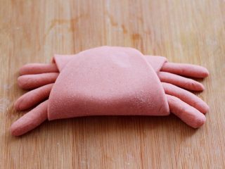 9、花样小螃蟹馒头,然后把面皮向上卷，包括住螃蟹的腿，靠近自己的这端压在上面。