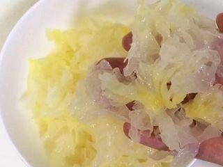 3、牛奶桃胶银耳羹,把银耳的根部去掉,照着它的纹理把它撕成片条状。