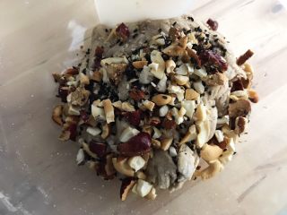 5、免揉黑糖干果软欧包,综合干果里枣子去核剪碎,坚果放在食品袋里用擀面杖敲碎,加入面团中混合,折叠翻拌。折叠翻拌的手法具体如下:用刮刀抄到面团底部,把面团拉扯起来,折叠并覆盖到面团上。转动容器,重复数次。