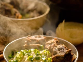 16、羊蝎子红汤面,把肉放入面上，撒上葱花