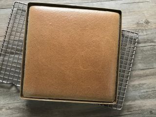 7、黑米戚风蛋糕卷,出炉震下模,蛋糕表面不是太烫时,烤网上垫张干净的油纸,将蛋糕倒扣在油纸上。