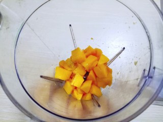 10、#冬喝暖饮夏吃冰#健康低卡-芒果酸奶昔,首先将切好的芒果肉加入料理机。(留两块果肉等一下做装饰)