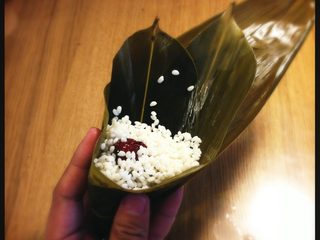 6、端午节 枣粽,糯米压实顶部，离粽叶边缘几毫米的距离，不要加的过满。同时手部形状改成托举状。粽叶尾部向外，如图：