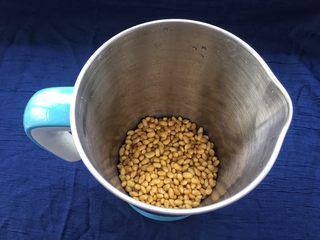 3、解渴消暑豆浆粥,泡好的黄豆清洗干净,沥干水分倒入豆浆机内(黄豆会有些细沙,灰尘什么的,需要清洗干净)。