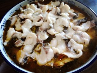 11、酸菜鱼,把鱼片平放在烧好的鱼头类上。