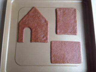 6、圣诞姜饼屋,将印好的饼干坯放在不粘烤盘上,每块饼干之间预留一点空间。(如果你怕移动中变形,也可以将面片移在烤盘上印出来,再去除多余的边角)