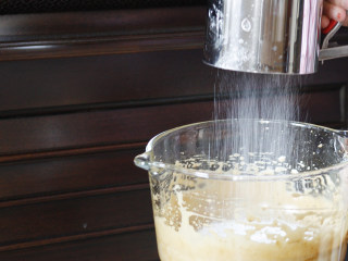 8、贝壳红枣小蛋糕,将低筋面粉、泡打粉和小苏打装入面粉筛，然后同时过筛进入打好的蛋糊中。建议分2-3次筛入，每次筛入都要用硅胶铲均匀的将面粉与蛋糊混合后再进行下一步。 以翻拌的形式操作，像制作戚风糊一样，既要使面粉完全消失干粉状，又不可以让打好的蛋糊过度消泡～