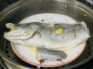 4、葱油鲈鱼,鲈鱼装盘，撒些料酒，面上和腹部也放一片姜，锅里水先烧开，然后大火上锅蒸7分钟左右；