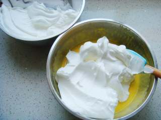 11、红枣葡萄干蛋糕杯,把打好的蛋白分一半倒入蛋黄糊糊里。呈“J”字形翻拌，不可划圈避免消泡。