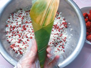 8、红豆红枣牛角粽,然后手捏住上面那一头粽叶转一圈,形成更长的牛角形状;