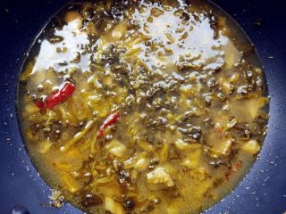 5、家常酸菜鱼,加入剁碎的腌萝卜（酱腌菜，没有可不加），鸡精，糖，白胡椒粉，盐和水（水量以与鱼片齐平为准），煮沸