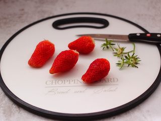 2、番茄草莓蜂蜜汁,用刀先把草莓的根蒂切出。