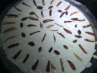 4、蒸米糕,如图盘子里铺上保鲜膜，刷一层橄榄油，将米糊倒入盘子中，表面摆上红枣丝和葡萄干