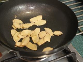 5、酒香麻油鸡油饭,先用白麻油2大匙将姜片小火慢慢煸香,煸至姜片快要卷曲。