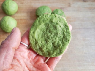 8、抹茶蜜豆华夫饼,将面剂子用手按扁，顺边沿向外捏开来成圆饼状（不需要擀面杖，直接手捏开就可以啦，揉透的面不粘手也不粘面板哦，如果你的面揉的不好也没关系，撒点手粉在面板上）。
