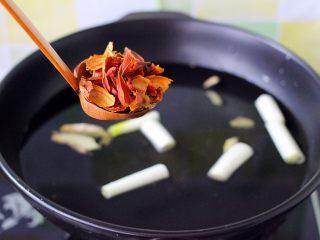 7、盐焗鸡,陶瓷炒锅里加入清水、放入切段的葱段和姜片、加入撬锁的栀子碎