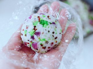 15、黎麦紫甘蓝时蔬饭团,手上铺上保鲜膜，放入适量的黎麦饭，随自己喜好，做成大小一样的圆团就可以了。