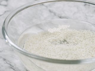 1、消暑仙草水果冰粥,糯米80g,洗净泡软,倒入电饭煲中,煮熟盛出晾凉