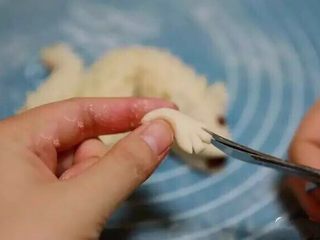 14、新年喜庆花样馒头,去一小块面团搓成长条，在一段剪三刀，做出小龙的爪子。