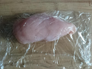 2、嫩煎鸡胸肉，健身减脂必备,用保鲜膜把鸡胸肉包起来。包起来的用意是，等下拍的时候肉末不会乱飞