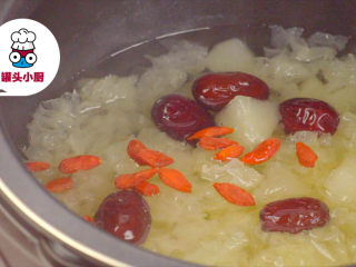 5、电饭煲银耳梨汤【罐头小厨】,开盖，放入洗净的枸杞15粒、老冰糖30g，盖上盖子继续炖煮10分钟