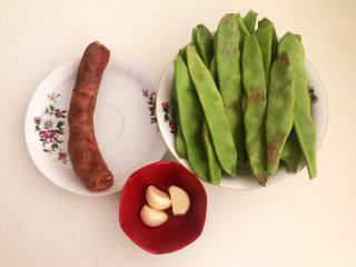1、爆炒豆角,准备好所有食材：一点红豆角，腊肠和蒜瓣