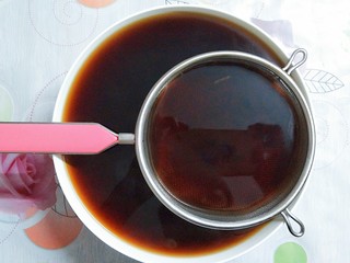 12、烧仙草红豆奶茶,准备好一个大碗和过滤网，把熬好的红茶倒入过滤网里，过滤掉茶叶！