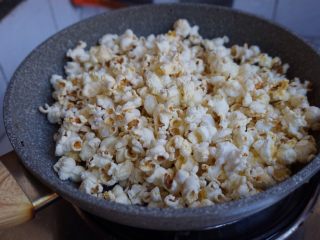 7、自制爆米花,5、很快就看到玉米粒在锅中跳舞变形，噼哩啪啦的声音非常好听。（摇晃一下平底锅）。看！小小一包就能爆出一大锅了。