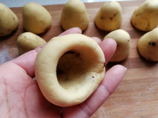 14、奶香玉米面窝窝头,再继续用大拇指旋转着把四周捏薄，边捏边向上顶一下，让它形成一个自然的窝头形状