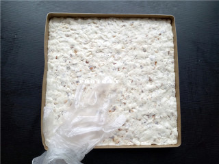 11、椰香牛轧糖,将牛轧糖从锅里倒出来，戴上食品级手套反复揉，便于散热；然后铺满烤盘，压实按平；